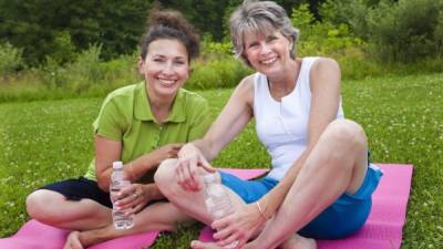 Two mature ladies share a laugh after yoga class.