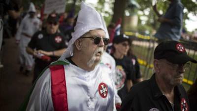 CHARLOTTESVILLE, VA - JULY 08: A Ku Klux Klan member is escorted out of Justice Park after a planned protest by the Klan on July 8, 2017 in Charlottesville, Virginia. The KKK is protesting the planned removal of a statue of General Robert E. Lee, and calling for the protection of Southern Confederate monuments. Chet Strange/Getty Images/AFP== FOR NEWSPAPERS, INTERNET, TELCOS & TELEVISION USE ONLY ==
