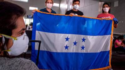 Un grupo de hondureños varados en Estados Unidos por el coronavirus sostienen la bandera nacional ante de subir a un avión en el Aeropuerto Internacional de Fort Lauderdale, a 40 kilómetros al norte de Miami, Florida (EEUU). EFE/Giorgio Viera/Archivo