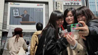 Adolescentes japonesas se toman un selfie mientras el portavoz del gobierno, Yoshihide Suga, anuncia la era Reiwa. AFP