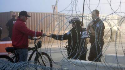 Un miembro de la Policía Fronteriza de los EEUU controla el documento de un hombre en el puente internacional de Texas. Foto: AFP