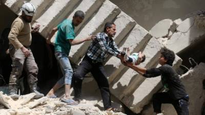 Voluntarios sacan de entre los escombros de un edificio bombardeado a un bebé en al-Kalasa en el norte de Alepo. Foto: AFP