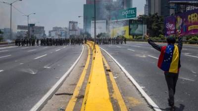 Con los brazos en alto, un manifestante camina hacia las fuerza del gobierno en Caracas.