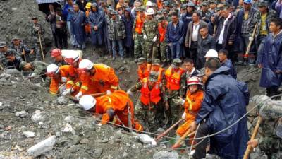 In this picture taken on June 24, 2017, rescue workers search for survivors at the site of a landslide in Xinmo village, Diexi town of Maoxian county, Sichuan province.Rescuers dug through earth and rocks for a second day on Sunday in an increasingly bleak search for some 118 people still missing after their village in southwest China was buried by a huge landslide. Rescuers have pulled 15 bodies from the avalanche of rocks that crashed into 62 homes in Xinmo, a once picturesque mountain village nestled by a river in Sichuan province. / AFP PHOTO / STR / China OUT