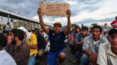 A Honduran migrant taking part in a caravan heading to the US, holds up a sign reading 'Thank you Mexico for opening your hearts to us', while he waits to cross the border from Ciudad Tecun Uman in Guatemala, to Ciudad Hidalgo, Mexico, on October 22, 2018. - President Donald Trump on Monday called the migrant caravan heading toward the US-Mexico border a national emergency, saying he has alerted the US border patrol and military. (Photo by ORLANDO SIERRA / AFP)