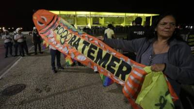 BRA117. BRASILIA (BRASIL), 18/05/2017.- Una manifestante sostiene una pancarta pidiendo la renuncia del presidente de Brasil Michel Temer hoy, jueves 18 de mayo de 2017, durante una protesta hoy, jueves 18 de mayo de 2017, frente al Palacio del Planalto en Brasilia (Brasil). EFE/Joédson Alves.