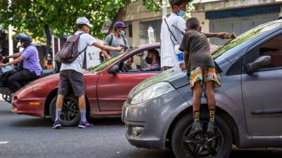 Varios niños y jóvenes migrantes limpian las ventanas de los carros.