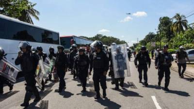 Mexican Federal Police officers are deployed on the road linking Ciudad Hidalgo and Tapachula, Chiapas state, Mexico, as a caravan of Honduran migrants heading to the United States takes place, on October 21, 2018. - Thousands of Honduran migrants resumed their march toward the United States on Sunday from the southern Mexican city of Ciudad Hidalgo, AFP journalists at the scene said. (Photo by Johan ORDONEZ / AFP)
