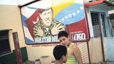 Un cartel pintado en la pared de una casa de Cienfuegos muestra a Hugo Chávez con las banderas de Cuba y Venezuela de fondo