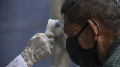 Personal médico toma la temperatura a un hombre en El Salvador. Foto: AFP