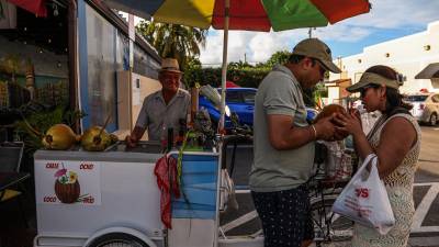 Una pareja comparte un agua de coco en la popular calle ocho de Miami, ciudad afectada por una ola de calor.