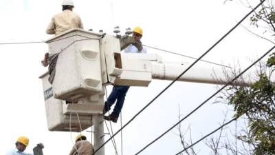 Empleados de la Empresa Nacional de Energía Eléctrica (Enee) trabajan en un poste de energía.
