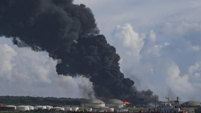 Humo negro de un tanque de petróleo en llamas se ve en Matanzas, Cuba, el 6 de agosto de 2022.- Aviones con productos, bomberos y especialistas de México y Venezuela llegaron a Cuba para ayudar a apagar este domingo el incendio de dos tanques de petróleo, que Entra en su tercer día con un muerto, 17 desaparecidos y 36 hospitalizados.
