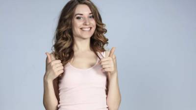 The young woman&#39;s portrait with happy emotions on gray background