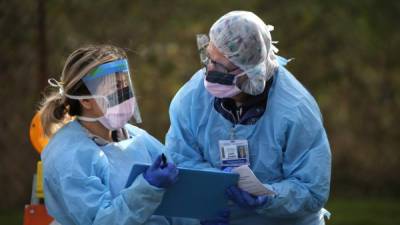 Dos enfermeras en EEUU se protegen con un traje del Covid-19. Foto: AFP