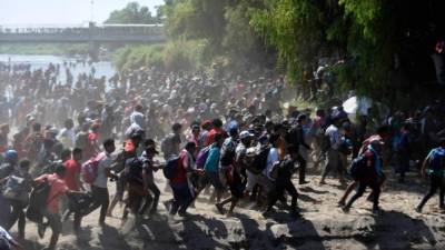 Los migrantes centroamericanos, en su mayoría hondureños, que viajan en caravana a los Estados Unidos, corren después de cruzar el río Suichate, la frontera entre Guatemala y Ciudad Hidalgo, México. AFP