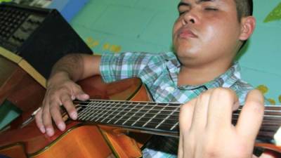 Mauricio Cáceres, un graduado, toca la guitarra.