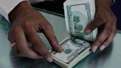 Un cajero de una institución bancaria cuenta dólares de diferentes denominaciones.