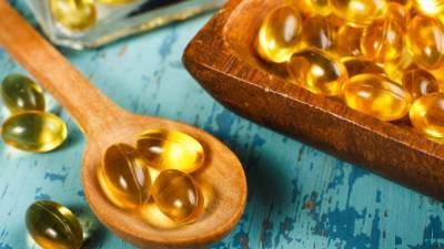 Cod Liver Oil Capsules on wooden spoon