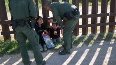 Los agentes de la patrulla hablan con una madre y una hija en la valla fronteriza en Texas. AFP