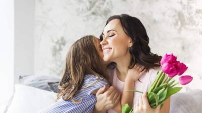 Young woman with tulips embrace with small girl