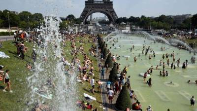Parisinos tratan de refrescarse en las fuentes de los Jardínes de Trocadero, junto a la famosa Torre Eiffel.