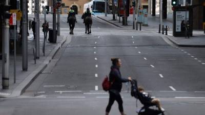 Una mujer se abre paso por una calle tranquila en el distrito comercial central de Sydney el 31 de julio de 2021, mientras las autoridades se apresuran a contener un brote emergente de la cepa Delta. (Foto de DAVID GRAY / AFP)