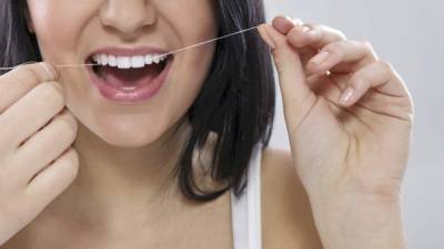 El movimiento correcto al usar el hilo dental es de arriba y abajo por los lados de los dientes.
