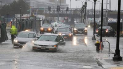 Vehículos se movilizan por las inundadas calles de la ciiudad de Boston.