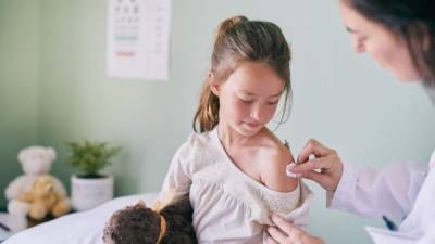 Shot of a pediatrician cleaning her young patients arm with a cotton ball