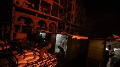 Trabajadores vacían un camión que contenía ayuda humanitaria, bajo la supervisión de la Organización de las Naciones Unidas (ONU), la Media Luna Roja Siria y el Comité Internacional de la Cruz Roja (CICR), en Douma, (Siria). EFE