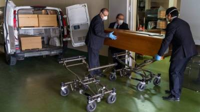 Empleados de una morgue descargan el ataúd de una víctima del coronavirus desde Madrid a San José en Burgos. Foto: AFP