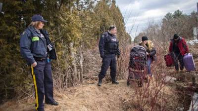 Agentes canadienses experan a una pareja que cruza ilegalmente la frontera entre EUA a Canadá. AFP.