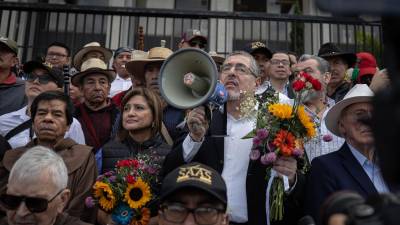 El presidente electo de Guatemala, Bernardo Arévalo de León (c), acompañado de su vicepresidenta, Karin Herrera (c-i), y junto a varios simpatizantes, habla antes de iniciar una marcha hoy, en la entrada de la Corte Suprema de Justicia en Ciudad de Guatemala.