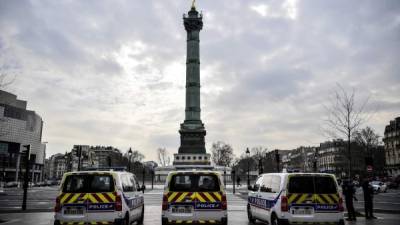 Los agentes de policía franceses se paran junto a sus vehículos mientras realizan controles en los conductores en la Place de la Bastille en París. Foto: AFP