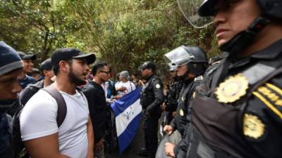 Migrantes hondureños intentan pasar un cerco policial en la frontera de Guatemala./AFP.