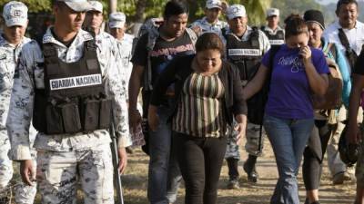 Una familia de migrantes es escoltada por miembros de la Guardia Nacional Mexicana y oficiales del Instituto de Migración después de ser detenidos cruzando el río Suchiate. AFP