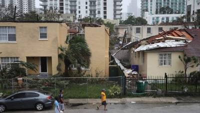 MIAMI, FL - SEPTEMBER 10: People walk past a building where the roof was blown off by Hurricane Irma on September 10, 2017 in Miami, Florida. Hurricane Irma, which first made landfall in the Florida Keys as a Category 4 storm on Sunday, has weakened to a Category 2 as it moves up the coast. Joe Raedle/Getty Images/AFP== FOR NEWSPAPERS, INTERNET, TELCOS & TELEVISION USE ONLY ==