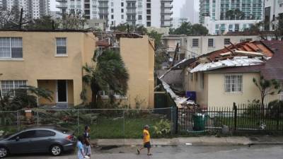 MIAMI, FL - SEPTEMBER 10: People walk past a building where the roof was blown off by Hurricane Irma on September 10, 2017 in Miami, Florida. Hurricane Irma, which first made landfall in the Florida Keys as a Category 4 storm on Sunday, has weakened to a Category 2 as it moves up the coast. Joe Raedle/Getty Images/AFP== FOR NEWSPAPERS, INTERNET, TELCOS & TELEVISION USE ONLY ==