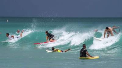 Grupos de personas practican surf este lunes, en la playa de Miami Beach, Florida (EE.UU.), aprovechando las olas que preceden la llegada del huracán Dorian. EFE/Giorgio Viera