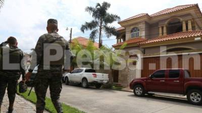 Elementos de la Policía Militar resguardan la residencia en la colonia El Pedregal de San Pedro Sula, asegurada al dueño de autolote New Orleans.
