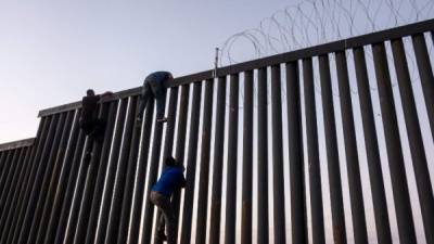 Los migrantes siguen desafiando a los militares y a Trump escalando la valla fronteriza en Tijuana./AFP.