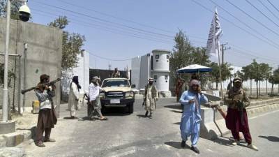 Los talibanes ondean su bandera mientras protegen la entrada del palacio presidencial en Kabul tras tomar la ciudad./AFP.