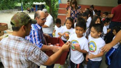 Manuel Alfaro (camiza azul) reparte porciones de frutas a escolares en San Pedro Sula. Fotos: Franklyn Muñoz
