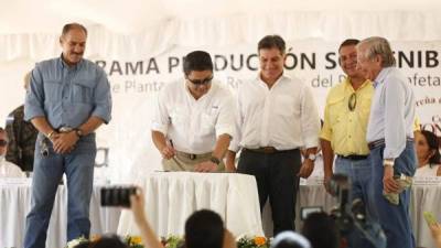 El presidente Juan Orlando Hernández firma el convenio ante la mirada de Mateo Yibrín, Jacobo Paz y otros empresarios.