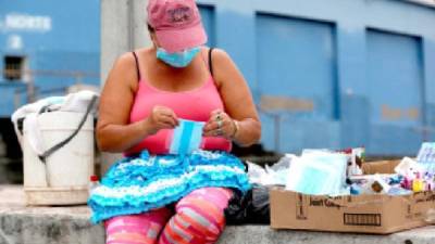 Una mujer vende mascarillas y golosinas en una caja de cartón en Tegucigalpa. Foto: EFE