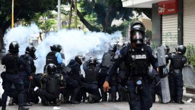 Riot policemen fire tear gas as they clash with high school and National Institute of Professional Training (INFOP) students during a protest against Honduran President Juan Orlando Hernandez in the surroundings of the Congress building in Tegucigalpa, on May 22, 2019. - The students demand the Congress to derogate at leat 11 decrees regarding health and education. (Photo by ORLANDO SIERRA / AFP)