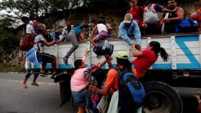 Migrantes hondureños que van en caravana hacia la frontera de México suben a camiones para ir a la Ciudad de Guatemala y aprovechan un cruce donde transita transporte pesado en el departamento de Zacapa (Guatemala). EFE