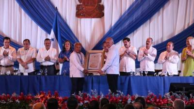 El pintor sampedrano recibe el pergamino de manos del presidente del Congreso Nacional, Mauricio Oliva; observa la directiva del Legislativo.