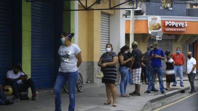 Las autoridades de Salud recomiendan no salir de no ser necesario. Sampedranos hacen fila para entrar a un banco.